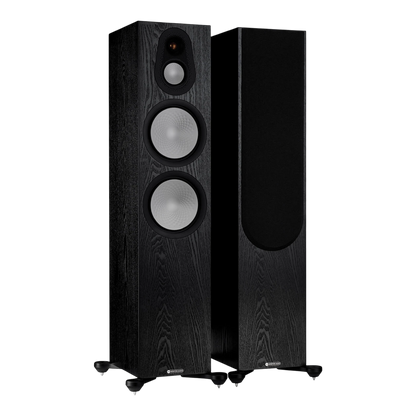 Salon 1 Audio Monitor Audio Silver 500 7G black floorstanding speakers with exposed drivers and one with grille on.