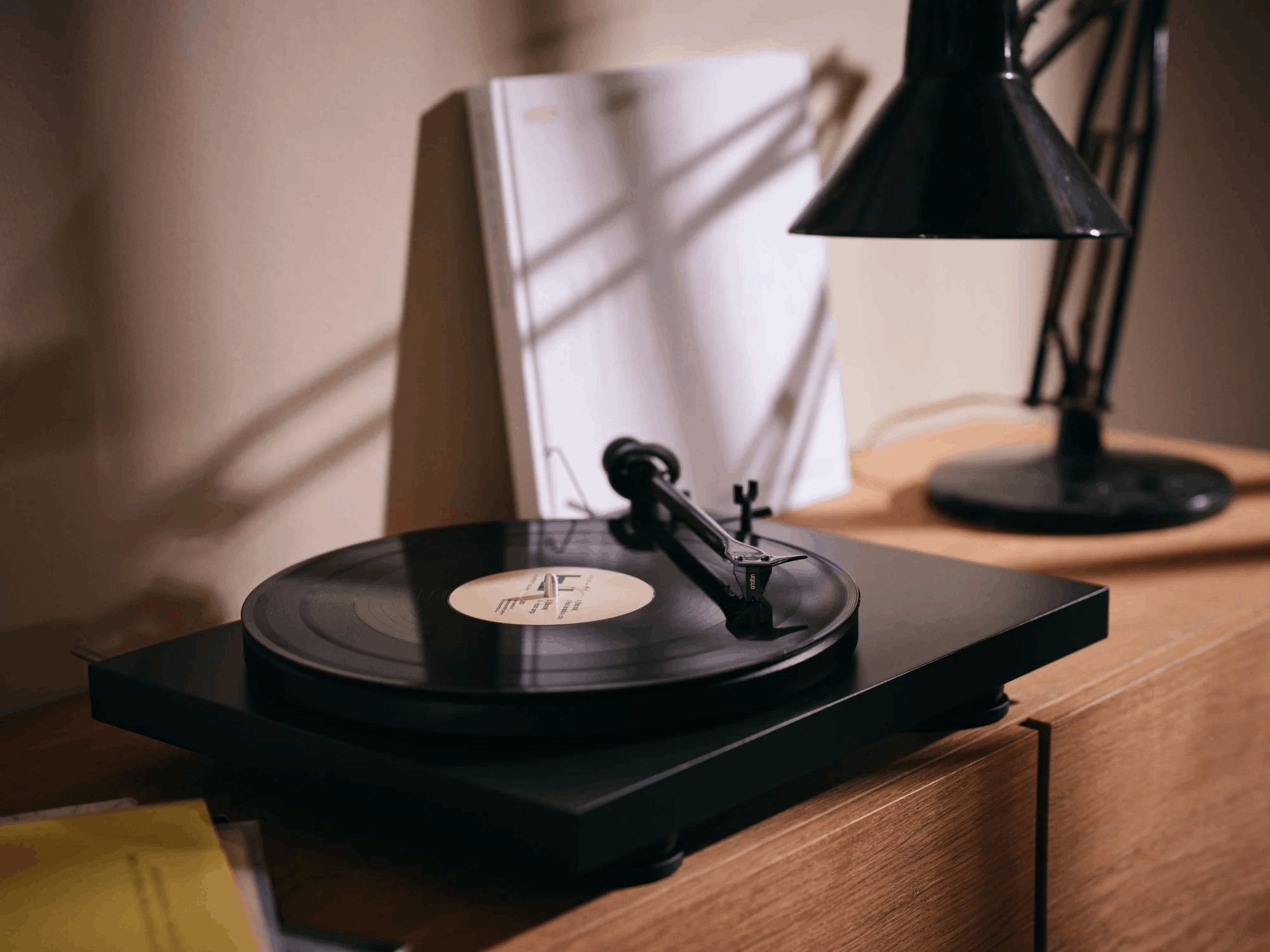 Salon 1 Audio Ortofon 2M Black moving magnet cartridge installed on a black turntable in a warm, dimly lit room.