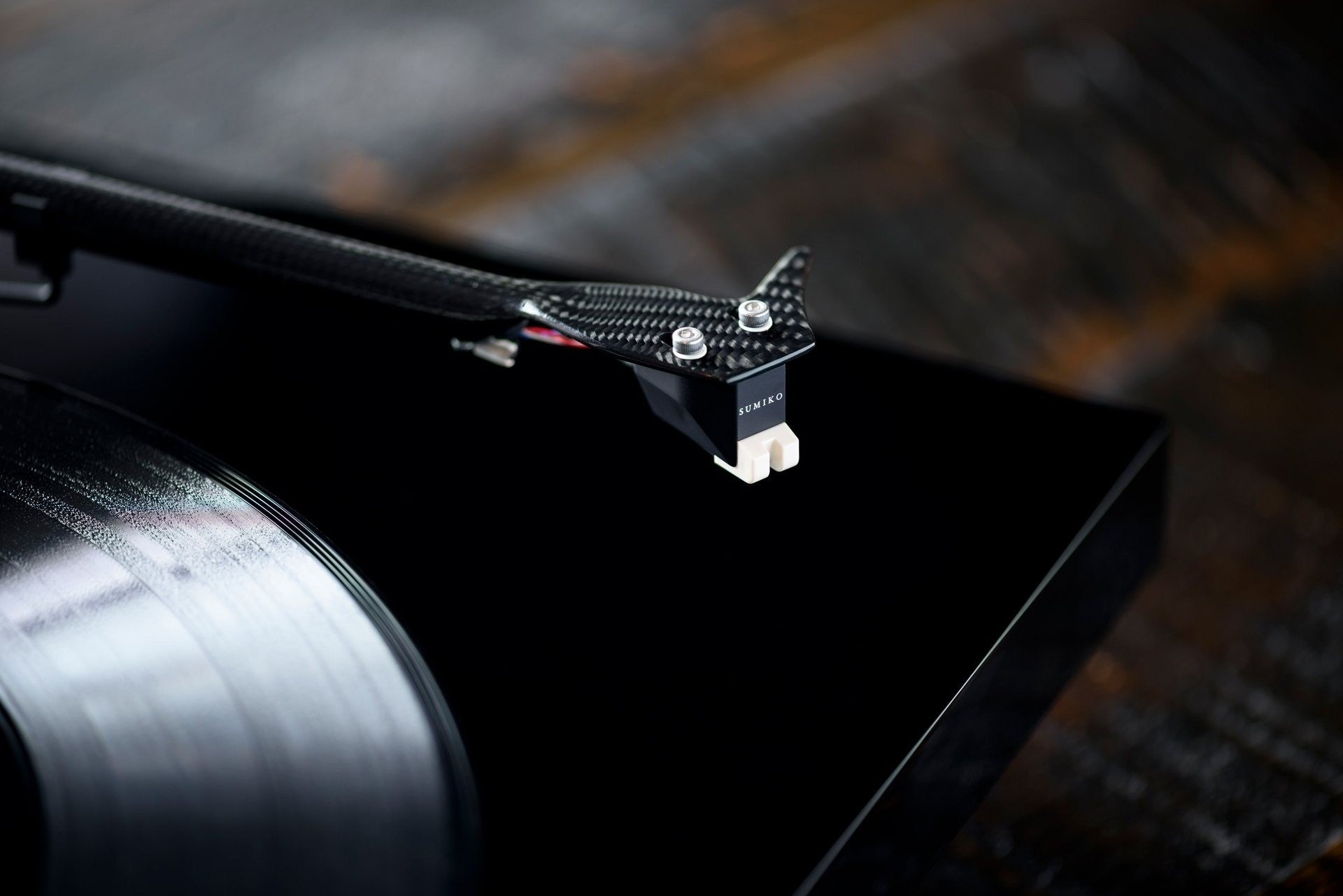 Salon 1 Audio Sumiko Rainier moving magnet phono cartridge mounted on a carbon fiber tonearm above a vinyl record.